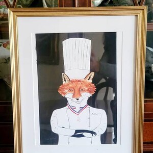 May include: A framed print of a fox wearing a chef's hat and a white chef's coat. The fox is standing with its arms crossed and has a serious expression on its face. The print is signed "Richard 19".