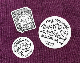May include: Three round stickers with black text on a white background. The first sticker features a book with the text "The Collected Works of Jane Austen". The second sticker features the text "my courage ALWAYS RISES at every attempt to INTIMIDATE me elizabeth bennet". The third sticker features the text "obstinate headstrong girl JANE AUSTEN".