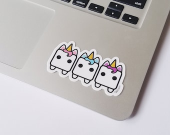 May include: Three white unicorn stickers with pink, blue, and yellow horns on a silver laptop.