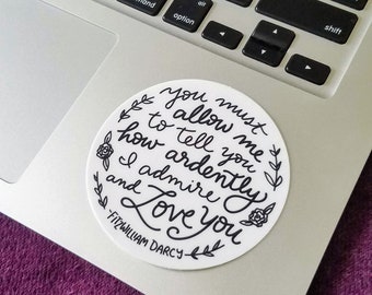 May include: A white round sticker with black lettering and floral accents. The sticker features a quote from the novel Pride and Prejudice by Jane Austen: "You must allow me to tell you how ardently I admire and love you." -Fitzwilliam Darcy.