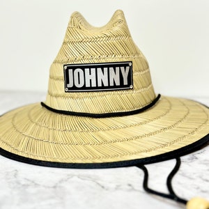 May include: A straw hat with a black band and a black patch with the word "JOHNNY" in silver lettering.