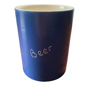 May include: A blue ceramic mug with the word "Beer" written on it in white.