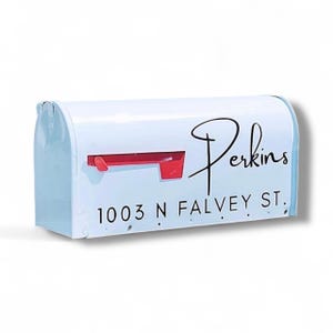 May include: White mailbox with the name "Perkins" in black script. The address "1003 N FALVEY ST." is printed below in a smaller, black font. The mailbox has a red flag and a curved top.