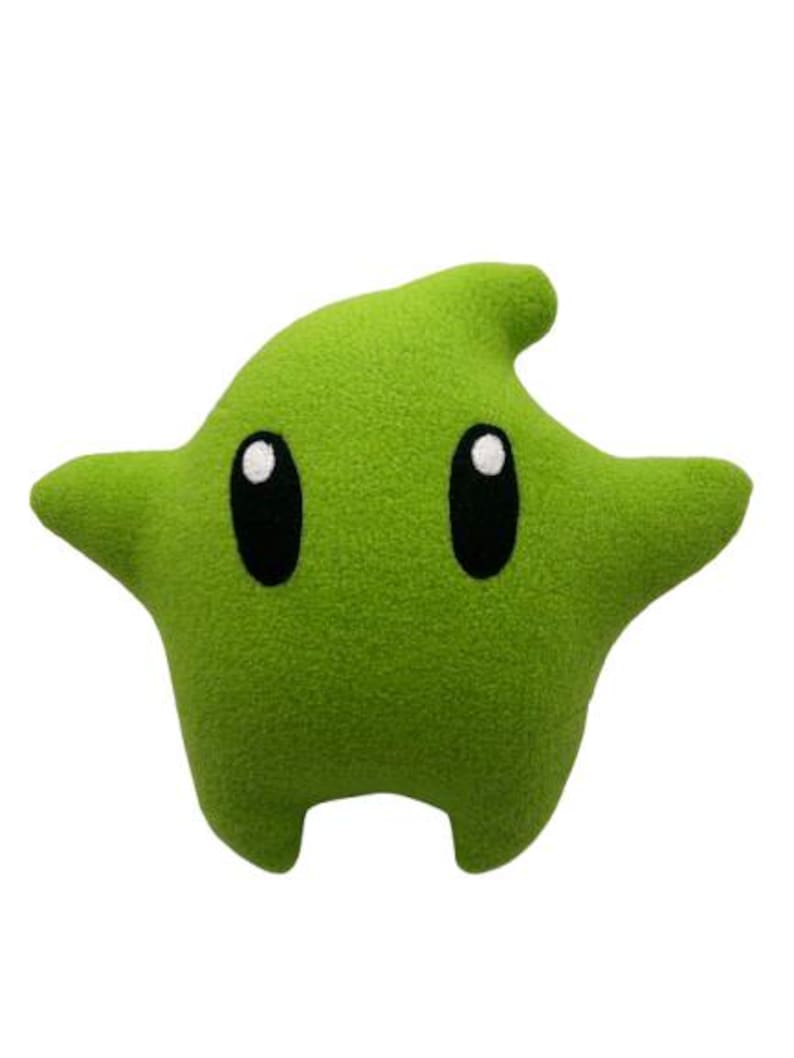 May include: A lime green star-shaped plush pillow with two large, oval black eyes and white highlights. The pillow has a textured surface and a small, pointed protrusion on top. The overall shape is reminiscent of a cartoon character.
