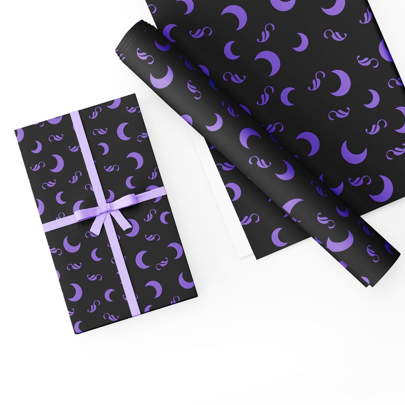 May include: A black gift box with a purple ribbon and a crescent moon pattern. The box is wrapped in black paper with a repeating pattern of purple crescent moons.