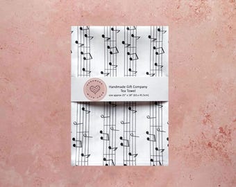 May include: White tea towel with a black musical note pattern. The towel is 25 inches by 18 inches. The text "Handmade Gift Company Tea Towel" is printed on a white label.