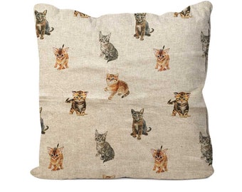 May include: A beige linen pillow cover with a repeating pattern of brown, black, and orange kittens. The kittens are all in different poses, some sitting, some standing, and some looking at the camera.
