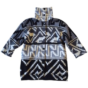 May include: A long-sleeved, button-down sweater in a geometric pattern. The sweater features a high collar and a color scheme of black, white, and various shades of gray. The design includes repeating geometric shapes.