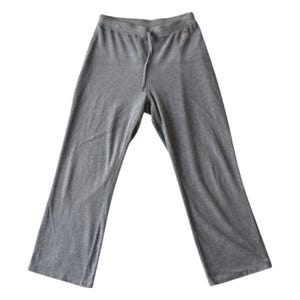 May include: A pair of gray sweatpants with a drawstring waist. The pants have a relaxed fit and wide legs, made of a soft, comfortable material. The casual pants are suitable for lounging or light activity.