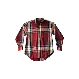 May include: A long-sleeved, button-down shirt in a plaid pattern of red, yellow, green, and white. The shirt has a single chest pocket and a button-down collar. The brand name "Nautica" is visible on the collar.