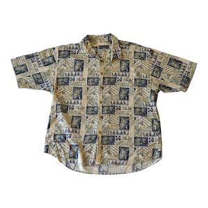 May include: Short-sleeved button-down shirt featuring a repeating pattern of squares in beige, green, and navy blue. The shirt has a classic collar and a relaxed fit, suitable for casual wear.