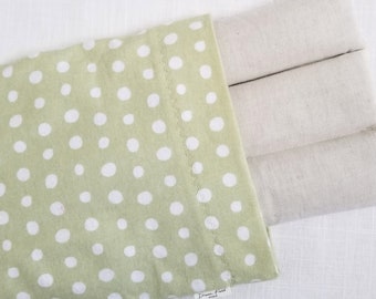May include: A green and white polka dot heating pad cover with three beige rectangular inserts. The cover is light green with white polka dots. The inserts are a light beige color. The product is on a white surface.