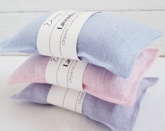 May include: Three lavender-filled sachets in pastel colors: light blue, pink, and lavender. Each sachet is wrapped with a white label that reads "Dream Studio" and "Lavender Organic Lavender / Eucalyptus". The sachets are stacked on top of each other.
