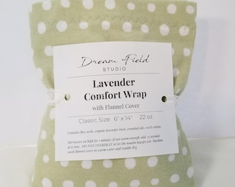 May include: A sage green flannel comfort wrap with white polka dots. A white paper label is attached, reading: Dream Field Studio, Lavender Comfort Wrap with Flannel Cover, Classic Size: 6" x 14", 22 oz. Includes instructions for microwave use.