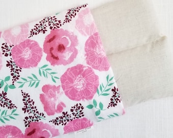 May include: A floral print fabric pouch with a cream-colored linen pouch peeking out. The floral print features large pink flowers, green leaves, and purple accents on a white background. The pouch is likely used for aromatherapy or storage.