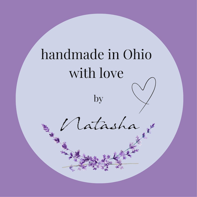 Op de afbeelding: Een ronde, lichtpaarse sticker met de tekst "handmade in Ohio with love by Natasha". Een zwart hart en een lavendel takje zijn ook inbegrepen. De achtergrond is een donkerdere tint paars.