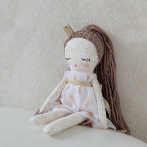 May include: A handmade doll with a white dress, gold trim, and brown yarn hair. The doll is wearing a gold crown and has painted eyes and freckles.
