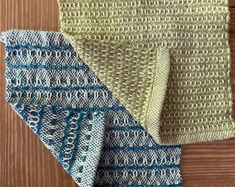 May include: Two woven fabric squares, one in a light green and white pattern and the other in a blue and white pattern.