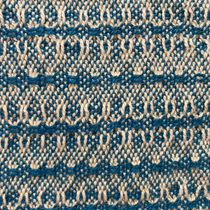 May include: Close-up of a woven fabric with a repeating pattern of white and blue. The fabric has a textured surface and a subtle sheen.