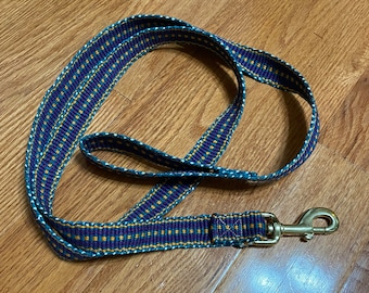 May include: A blue, purple, and gold dog leash with a gold metal clip.