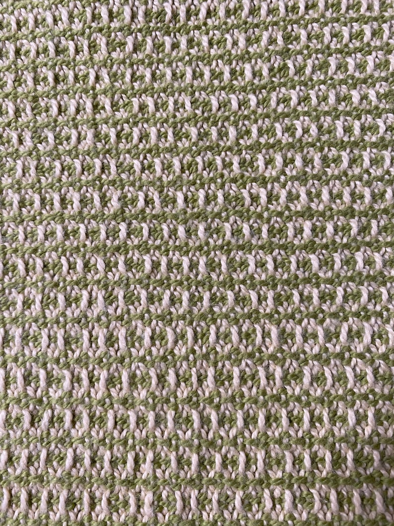 May include: Close-up of a woven fabric with a green and white checkered pattern. The fabric has a textured, slightly rough surface.