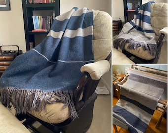 May include: A blue and white striped throw blanket with fringe on a chair. The blanket is woven on a loom in the background.
