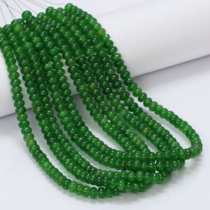 Può includere: Una collana di perle di giada verde, infilate su un filo d'argento. Le perle sono rotonde e lisce, e sono tutte più o meno della stessa dimensione.