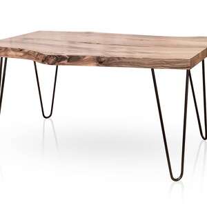 May include: A wooden coffee table with a natural wood finish and a live edge top. The table has four hairpin legs made of black metal.