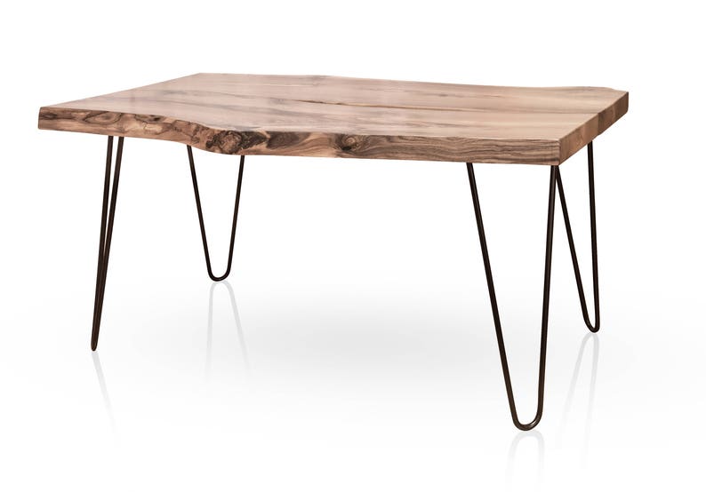 May include: A wooden coffee table with a natural wood finish and a live edge top. The table has four hairpin legs made of black metal.