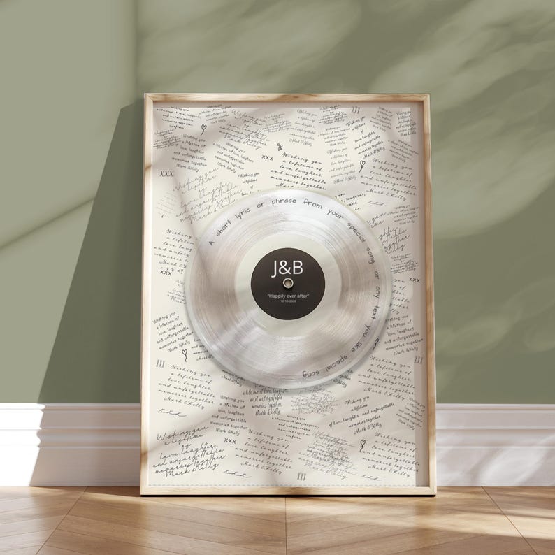 May include: A framed wall art piece featuring a clear vinyl record centered on a cream-colored background covered in repeated handwritten text. The record label is black with white text reading J&B, Happily ever after, and 10.14.2023.
