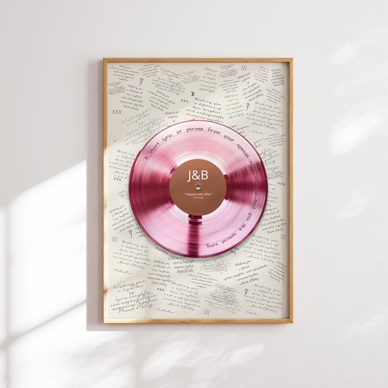 May include: A framed wall art piece featuring a translucent pink vinyl record centered over a cream-colored background filled with repeating handwritten text. The record label is brown with the white text J&B and Happily ever after.