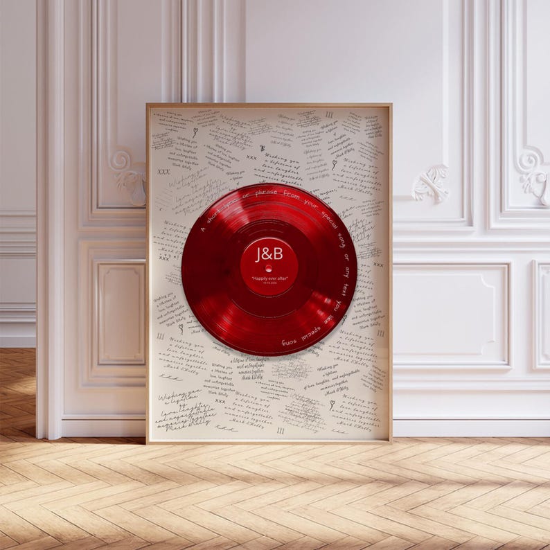 May include: A framed wall art piece featuring a glossy red vinyl record centered on a light-colored background covered in repeating handwritten text. The record label displays the letters J&B and the text "happily ever after" in white.
