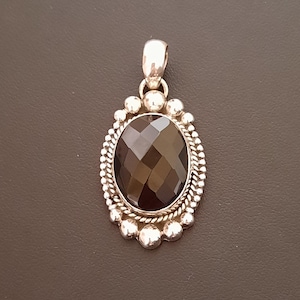 Colgante ovalado de plata con piedra de ónix negro facetada. 
El colgante está decorado alrededor de la piedra con bolitas e hilo torzal de plata.
