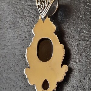 Puede incluir: Pendiente de plata con un dise&ntilde;o ornamentado y una gran abertura ovalada. El pendiente tiene un sello 925 en la parte posterior.