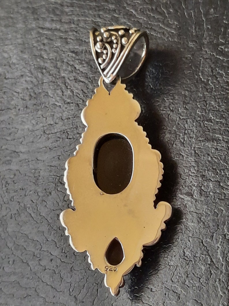 Puede incluir: Pendiente de plata con un dise&ntilde;o ornamentado y una gran abertura ovalada. El pendiente tiene un sello 925 en la parte posterior.