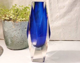 Könnte beinhalten: Eine kobaltblaue Glasvase mit einem klaren Glasfuß. Die Vase hat ein geometrisches, facettieres Design.