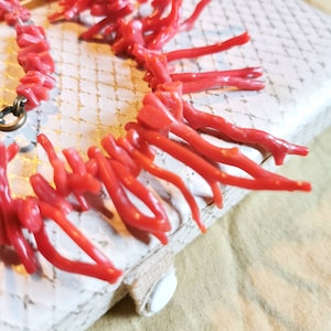 May include: A red coral necklace with a silver clasp. The necklace is made of many small, thin pieces of coral that are arranged in a cascading pattern.