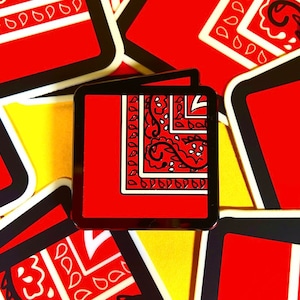 May include: A red and white bandana pattern enamel pin with a black border. The pin is on a yellow background with other red and white bandana pattern pins.