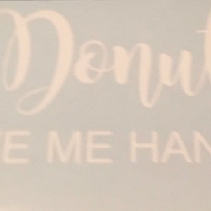 Puede incluir: Texto blanco sobre un fondo azul claro que dice "Donut LEAVE ME HANGING" en una fuente cursiva juguetona. La imagen es un primer plano, que destaca el diseño y el mensaje del texto.
