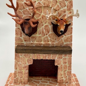 May include: A miniature fireplace with a brick facade and a wooden mantel. Two deer heads with antlers are mounted on the stone wall above the fireplace. The deer heads are brown and white.
