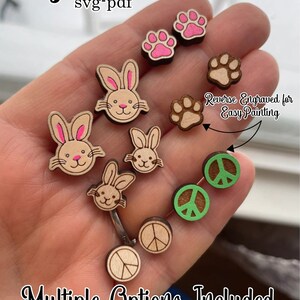 May include: Digital file download of SVG and PDF files for laser cutting. The image shows a variety of wooden cutouts, including bunnies, paw prints, and peace signs. The cutouts are designed to be painted after cutting.
