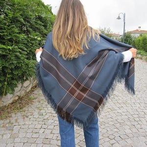 May include: A blue and brown plaid fringed shawl with a geometric pattern.