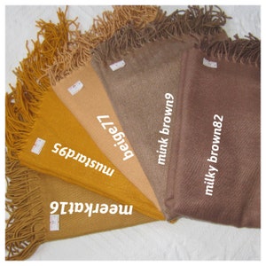 May include: Five different colored scarves with fringed edges. The colors are:  meerkatt, mustard, beige, mink brown, and milky brown. Each scarf has a label with the color name and number.