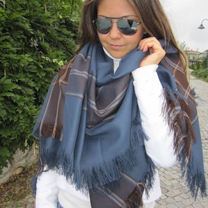 May include: A blue and brown plaid scarf with fringe. The scarf is wrapped around a person's neck and shoulders.