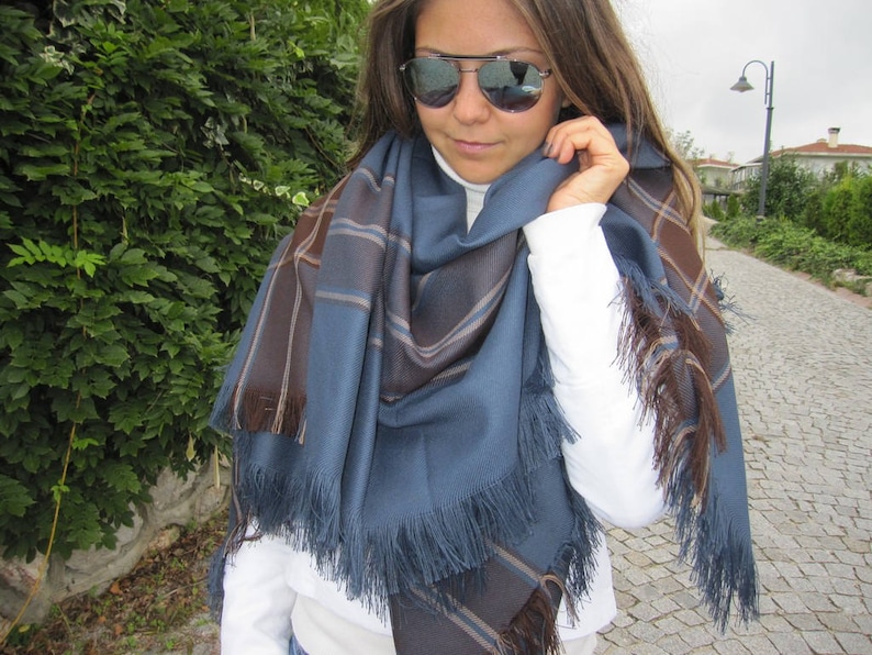 May include: A blue and brown plaid scarf with fringe. The scarf is wrapped around a person's neck and shoulders.