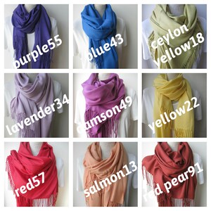 May include: Nine different colors of pashmina scarves with fringe. The colors are purple, blue, yellow, lavender, crimson, red, salmon, and red pear.