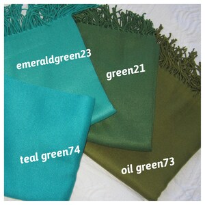 May include: Four different shades of green fabric swatches with fringed edges. The swatches are labeled "emerald green23", "green21", "teal green74", and "oil green73".