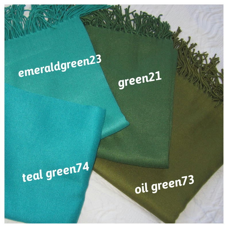 May include: Four different shades of green fabric swatches with fringed edges. The swatches are labeled "emerald green23", "green21", "teal green74", and "oil green73".