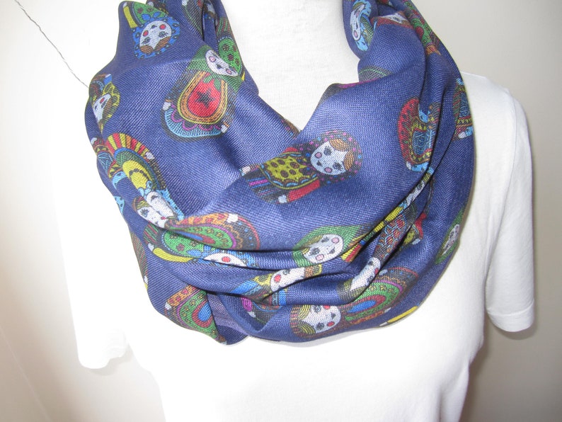 May include: A navy blue infinity scarf with a colorful pattern of Russian nesting dolls.