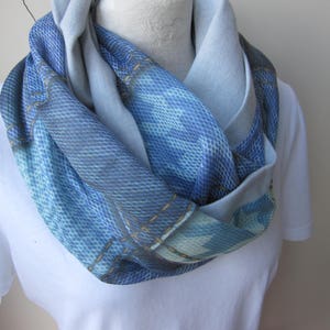 Puede incluir: Una bufanda infinita de patrón azul y blanco hecha de una tela suave. La bufanda está doblada por la mitad y drapeada alrededor del cuello de un maniquí.